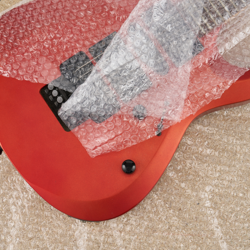 Luftpolsterfolie im Einsatz – Produktschutz: eine rote Gitarre in Folie eingewickelt.