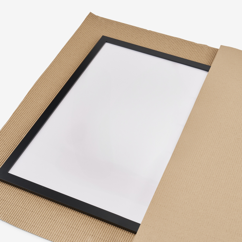 Verwendung von Wellpappe bei der Verpackung eines Bildes – Rahmen liegend auf Wellpappe, präsentiert auf grauem Hintergrund