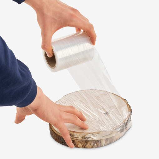 Mini-Stretchfolie in der Anwendung – ein Mann zieht die Folie über ein Produkt. Sie haftet gut und reißt nicht.