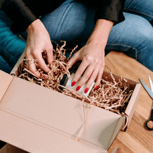Anwendung von SizzlePak - eine Person legt Papierstreifen in den Karton, um Produkte zu schützen.