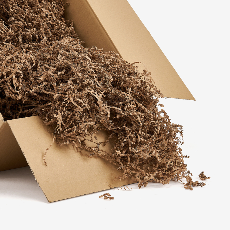 Kartonbox mit herausrieselnden Papierstreifen, bereit zum Sichern von Sendungen.