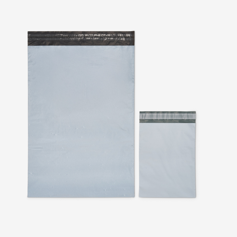 Großer und kleiner Versandbeutel aus Folie auf grauem Hintergrund