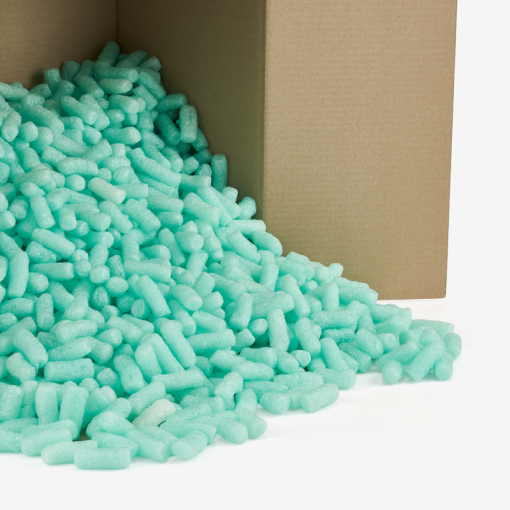 Grünes, biologisch abbaubares Skropak rieselt aus dem Karton.