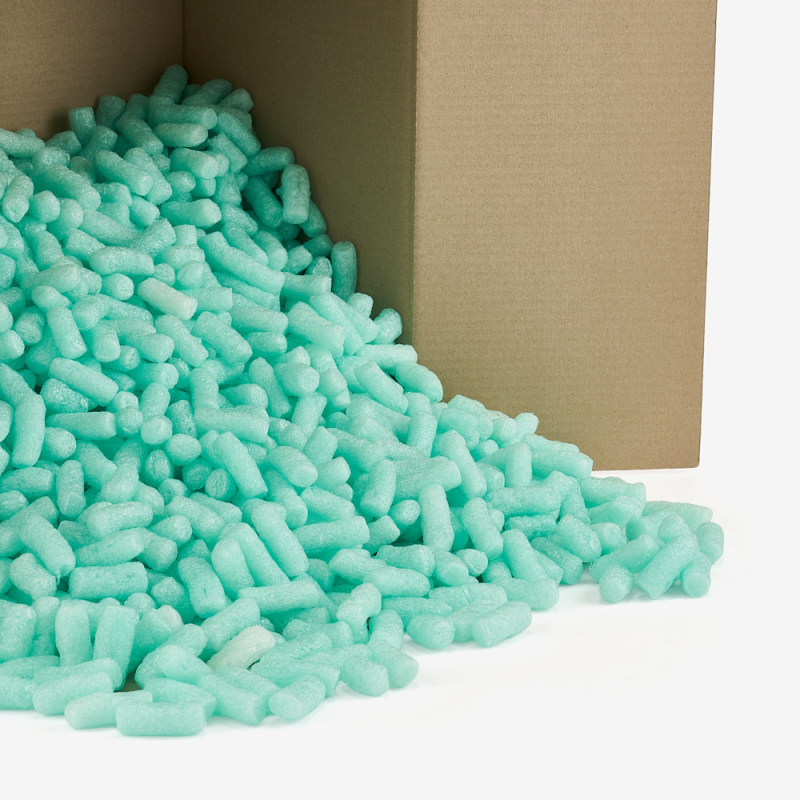 Grünes, biologisch abbaubares Skropak rieselt aus dem Karton.