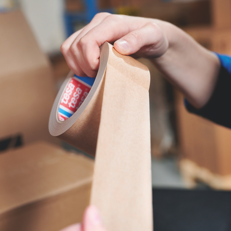 Nahaufnahme des manuellen Abrollens des TESA® 4713 Papierklebebands - betont seine Flexibilität und Benutzerfreundlichkeit.